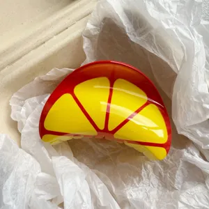 Close-up of a fruit lemon print hair claw clip in a beige packaging box