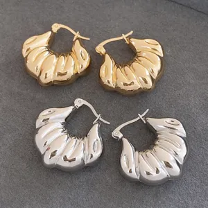 Gros plan détaillé de boucles d'oreilles créoles géométriques côtelées or et argent.
