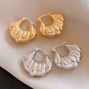 Gros plan détaillé de boucles d'oreilles créoles croissant en métal tendance or et argent.
