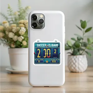 Vista detallada de funda de teléfono blanca con pegatina de marcador de fútbol en mesa.