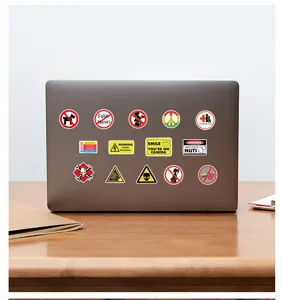 Detailansicht verschiedener Warn- und Graffiti-Aufkleber auf einem Laptop-Deckel am Holztisch.