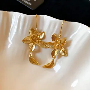 Orecchini a gancio con fiori dorati, eleganti gioielli pendenti floreali metallici minimal.