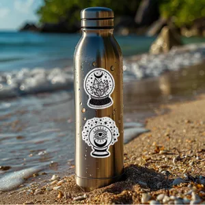 Gros plan de la bouteille d'eau en acier inoxydable décorée de stickers mystiques noirs.