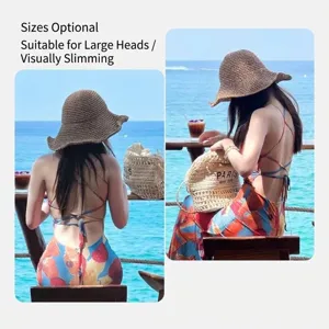 Model met een bruine, handgeweven strooien zonnehoed tegen een zonnige strandachtergrond