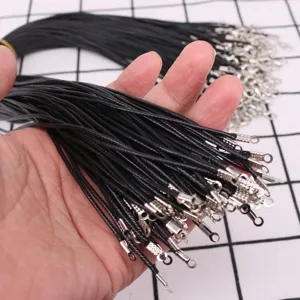 Close-up of bulk black waxed necklace cords with silver metal clasps held in hand