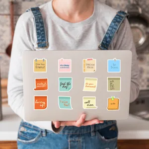 Primo piano di adesivi colorati a forma di foglietti con citazioni inglesi sul laptop.