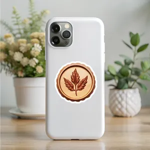Close-up detail of white phone case featuring retro leaf seal sticker on wooden desk setup.
