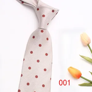 Detail view of a classic herringbone men's necktie with red polka dots and floral prop.