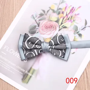 Detailed closeup of elegant grey patterned bow tie resting on a floral background prop.