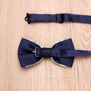 Men's two-tone bow tie detail view showing satin surface and floral underlayer craft.