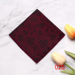 Detailopname van een bordeauxrode pochet met bloemenmotief op een marmeren achtergrond.