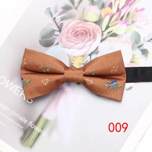 Primo piano del farfallino floreale marrone con intricato motivo di uccelli e fiori.