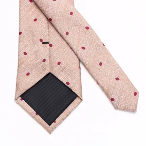 Detailed view of a gold men's necktie with burgundy polka dots and fine jacquard texture.