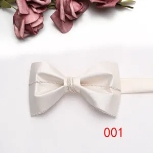 Dettaglio di un elegante farfallino in raso beige con catenina argentata per eventi formali.