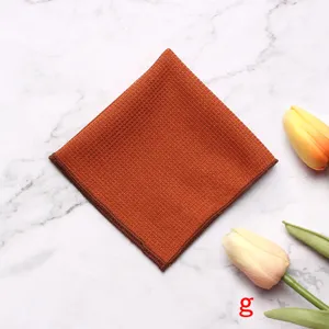 Detailansicht eines eleganten rostbraunen gestrickten Baumwolltuchs auf Marmor.