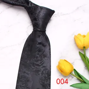 Close-up of a black jacquard pattern men's tie on marble background with yellow tulips.