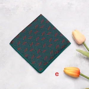 Dark green pocket square with red geometric pattern mens suit handkerchief accessory detail.