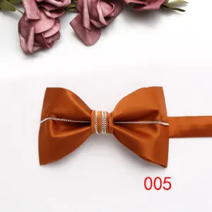 Dettaglio farfallino in raso arancione con catena d'argento, accessorio elegante per camicie.