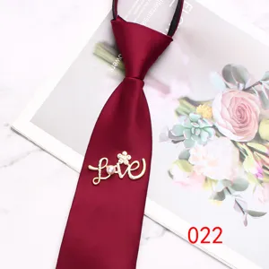 Close-up detail of burgundy zipper necktie with rhinestone love brooch, elegant accessory.