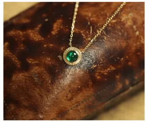 Close-up of emerald round pendant necklace in 14K gold plated silver