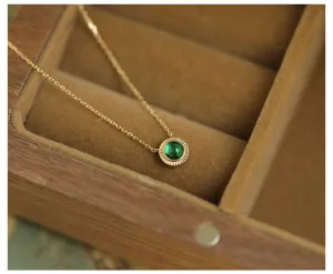 Close-up of elegant round emerald green pendant on a delicate gold plated silver chain