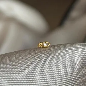 Detailaufnahme eines zierlichen goldenen Knorpelohrsteckers mit einem Kristalldetail