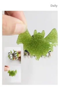 Detailed macro view showing the texture and metal claw of the green glitter bat hair clip