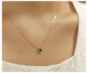 Macro view of a round green emerald pendant on a delicate 14K gold plated silver chain