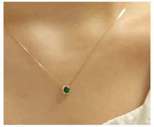 Close-up of a round emerald pendant on a delicate 14K gold plated silver chain