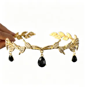 Detalle de una corona de novia dorada estilo bosque con cristales negros en gota y hojas.