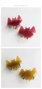 Detailed macro shot of fashionable red and gold glitter bat-shaped hair claw clips for women