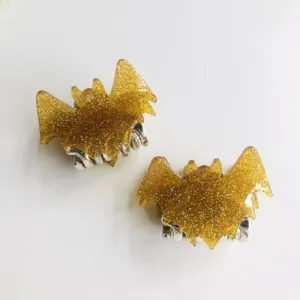 Pair of decorative glittery gold bat-shaped hair claw clips with silver metallic grip base
