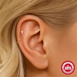 Nahaufnahme eines goldenen Knorpel-Piercing-Ohrrings mit Kristall und Kette am Ohr