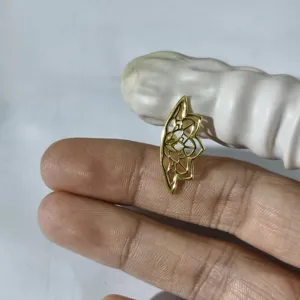 Makro-Detail eines goldenen Lotus-Knorpel-Ohrsteckers, zwischen Fingern gehalten