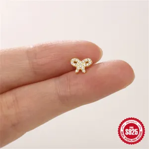 Nahaufnahme eines kleinen goldenen Schleifen-Piercing-Ohrrings am Finger