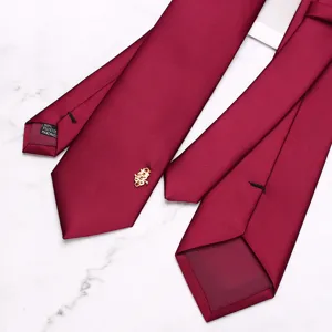Burgundy wedding tie detail showing smooth polyester fabric texture and traditional pin.