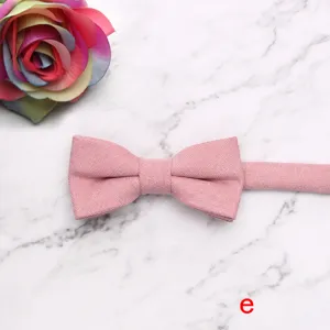 Detail shot of a pink solid color children bow tie on marble background with rose flower prop.