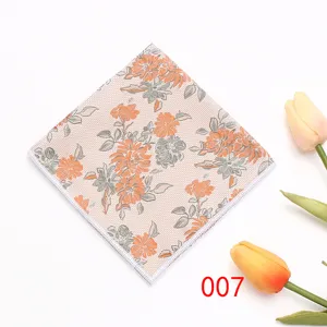 Detailopname van een elegant heren pochet met oranje bloemen en netjes afgewerkte randen.