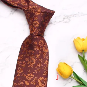 Detailed view of men's floral woven necktie in dark red with golden floral pattern.
