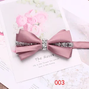 Dettaglio in primo piano di un elegante papillon in raso rosa con strass su sfondo floreale.