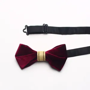 Velvet bow tie detail showing wine red fabric, gold center band and adjustable black strap.