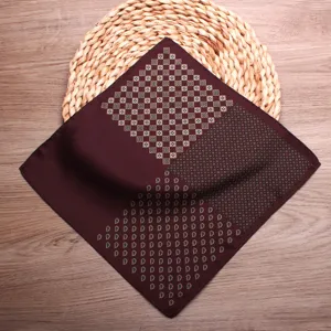 Detailed view of men's burgundy pocket square with geometric and paisley print patterns.