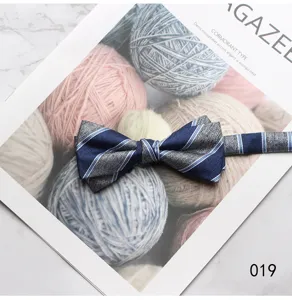 Detail shot of a stylish blue and grey striped men's bowtie placed on a chic yarn magazine prop.