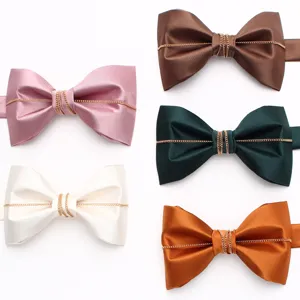 Primo piano di eleganti papillon da uomo in vari colori con decorazione a catena dorata sottile.