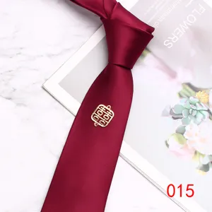 Burgundy wedding necktie fabric detail showing elegant golden double happiness symbol charm ornament.