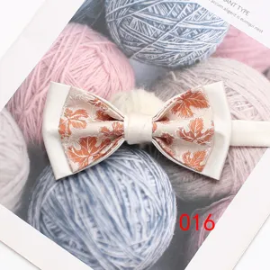 Vue détaillée d'un nœud papillon double blanc élégant avec motif de feuilles orange pour costume.