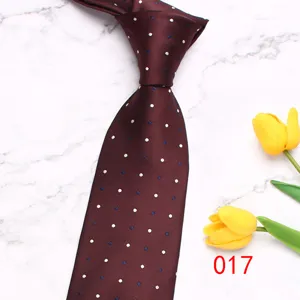 Primo piano dettaglio cravatta uomo bordeaux a pois su marmo con decorazioni di tulipani gialli.