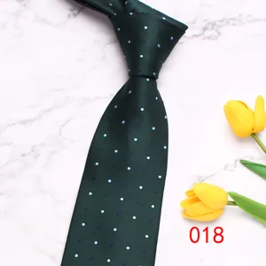 Vista dettagliata di una classica cravatta da uomo verde scuro con elegante motivo a pois bianchi.
