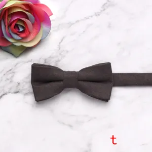 Detail view of solid dark brown velvet children bow tie presented on marble background.