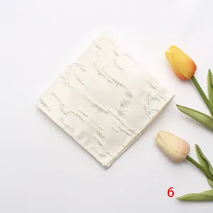 Detalle en primer plano de un pañuelo de bolsillo blanco de jacquard con motivo de hojas.